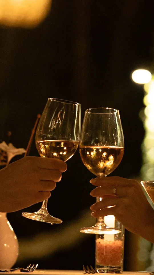 Duas taças de vinho branco num brinde à luz de velas